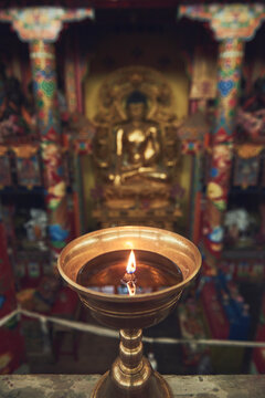 High angle of burning candle in candlestick lit for prayer in holy place in Buddhist temple in China