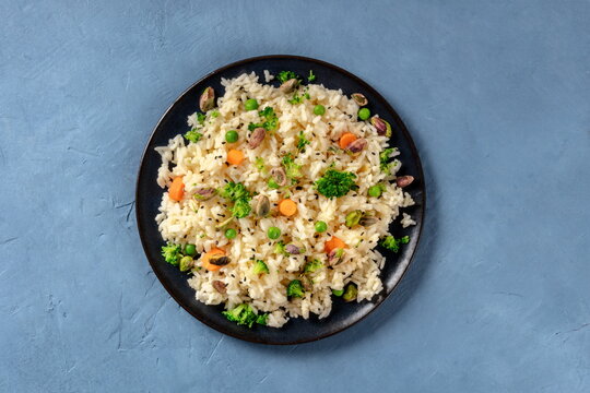 Vegan rice with vegetables, healthy and delicious, overhead shot on a blue background