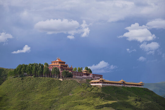 Picturesque scenery of green hill with Tibetan Buddhist temples on top located in village of Bamei in China