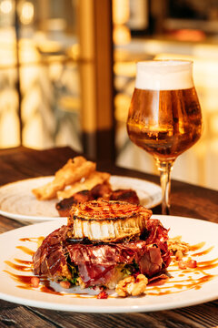 Delicious juicy grilled beef steak with seared cheese served with glass of cold beer in restaurant