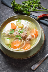 Meatball soup and ingredients on stone table.