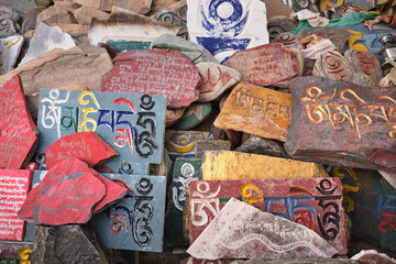 Overhead view of Sanskrit mantra Om Mani Padme Hum engraved on shabby surface of multi colored stone slabs in daylight