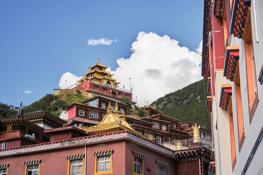Light blue sky covered with clouds over church near settlement and mountains covered with lush green forest