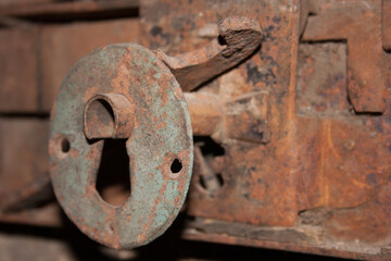 Close-up shot of an antique keyhole in a rusted iron plate on an old iron door.