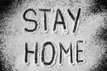 Round dark sign with the words "stay home" in the snow. Writing "Stay home" on the snow