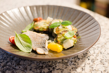 fried sea bass fillet with lemon and fresh vegetable salad close-up on a plate on the table.