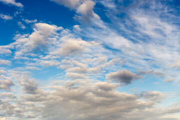 Background. A blue sky with white, airy, cumulus clouds.