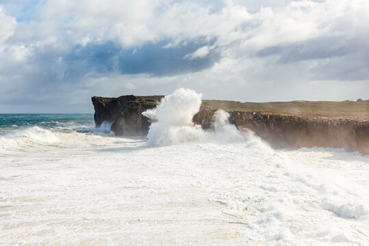Spectacular scenery of foamy sea waving over rough rocky cliff on sunny day in Bufones de Llames Pr&radic;&ne;a in Spain