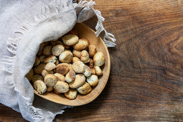 Lithuanian traditional Christmas Eve cookies kuciukai in linen bag on a wooden rustic board.