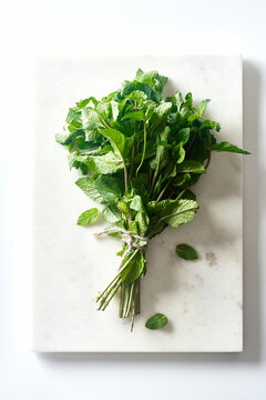 A bunch of fresh mint on marble cutting board