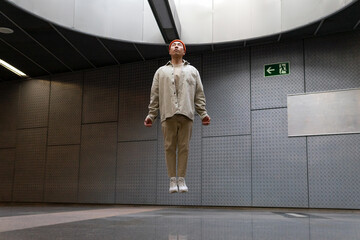 Full body focused stylist Asian male wearing casual outfit levitating with eyes closed above floor in building hallway