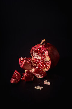 Fresh ripe halved pomegranate and seeds on black background