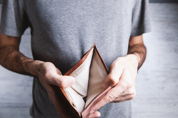 man holds an empty wallet in his hands.