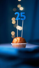 Birthday cupcake or muffin with number twenty five (25) and lights on the blue background. Birthday...