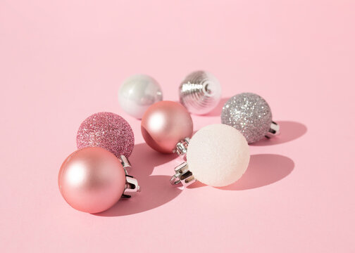 From above of decorative Christmas baubles arranged on pink background in studio for holiday celebration