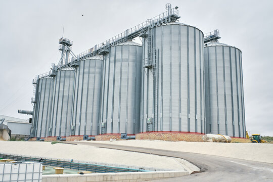 Low angle of huge steel agricultural silo towers located at factory area under cloudy sky