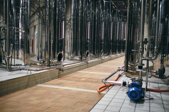 Rows of shiny stainless steel reservoirs placed in bright industrial area of modern factory