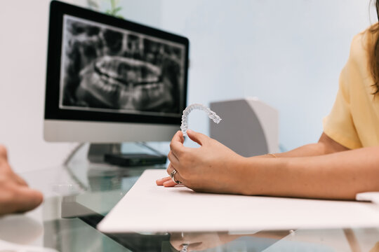 Dentist with invisible braces on his hands and an X-ray in the background