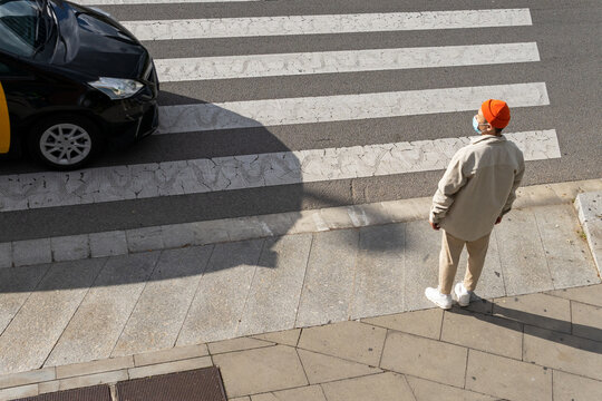 From above full body male pedestrian wearing casual outfit standing on roadside near crosswalk on sunny day