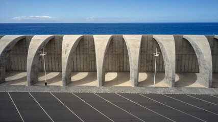 High angle of walkway with stone arched columns located near public parking on background of amazing seascape in summer