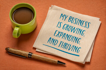 my business is growing, expanding, and thriving - handwriting on a napkin with a cup of coffee,...
