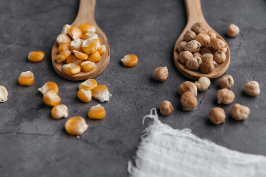 Top view of assorted dried ingredients placed in wooden spoons and scattered on black table in kitchen