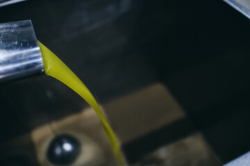 Closeup of yellow chemical liquid flowing from metal tap in industrial area of modern plant