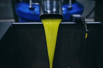 Closeup of yellow chemical liquid flowing from metal tap in industrial area of modern plant