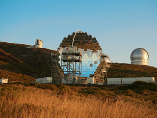 Various modern telescopes including MAGIC or Major Atmospheric Gamma Imaging Cherenkov Telescope located on hill slope at astronomical observatory on island of La Palma in Spain