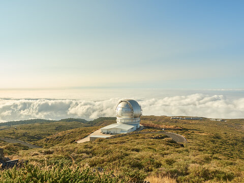 Largest optical reflecting telescope Gran Telescopio Canarias located on grassy hilltop against cloudy sky at astronomical observatory on island of La Palma in Spain