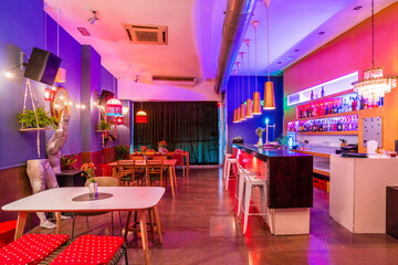 Interior of empty stylish bar with neon lights and modern design decorated with flowers and lamps