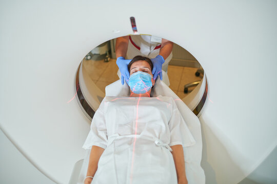 Anonymous doctor in uniform using tomography machine with lying female patient in hospital