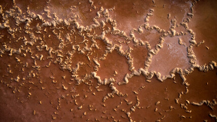 Textured background of weather metal wall with curved lines of corrosion on sunny day in city