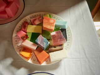 From above of pile of colorful pieces of natural handmade soap placed in plate on table