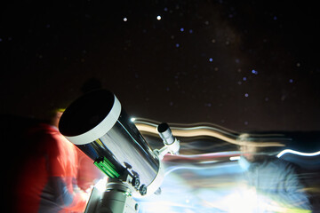 Blurred anonymous scientists using modern optical telescope and exploring stars at night time while working in observatory