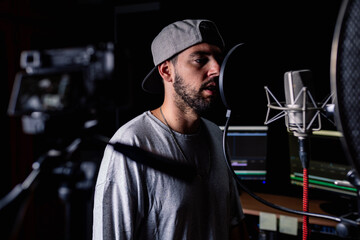 Confident male singer in music recording studio and shooting video on professional camera for blog