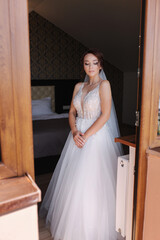 Portrait of elegant bride in fashion wedding dress stand on the balcony and posing to photographer