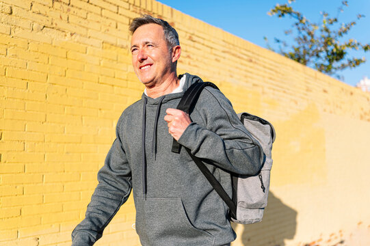 Senior retired man athlete walking with sportswear and backpack
