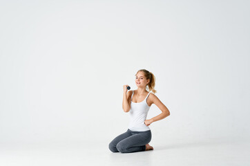 Fototapeta na wymiar woman in sweatpants sits on the floor with dumbbells in hands Fitness