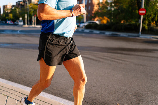 Unrecognizable senior retired man running through the city