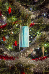 Christmas time during pandemic coronavirus. Medical mask on the christmas tree with decorations. Christmas 2020 in quarantine.