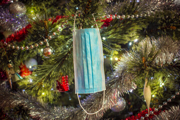 Christmas time during pandemic coronavirus. Medical mask on the christmas tree with decorations. Christmas 2020 in quarantine.