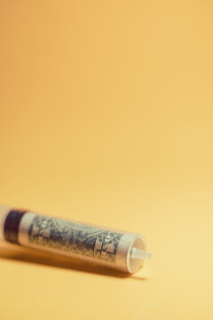One dollar banknote placed in medical syringe on light orange background showing concept of economic recovery