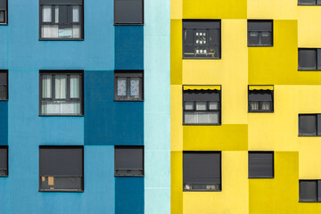Background of blue and yellow exterior of residential building with windows of various sizes in city