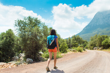 Naklejka premium A woman with a backpack is walking along a mountain road.