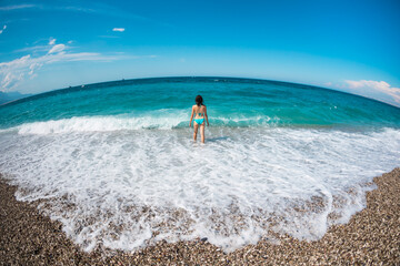 Fototapeta na wymiar A girl in a swimsuit walks along the beach