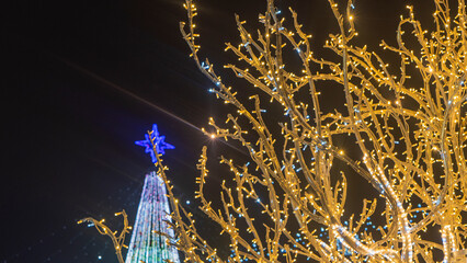 abstract Christmas tree and festive street garland light illumination unfocused. Holidays concept. Photo at night time.