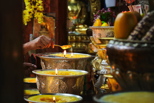 Crop hand of person with spoon making religious oriental rite near burning candles in local Buddhist shrine in China