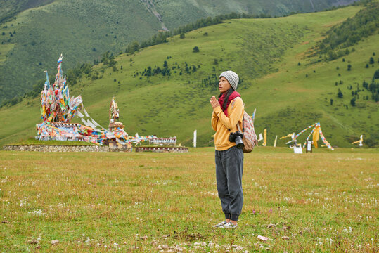 Full body of Asian female traveler standing with hands clasped in green village in China