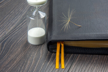 hourglass and bible with dandelion seed. sow the seed of faith in God. Christianity and religion